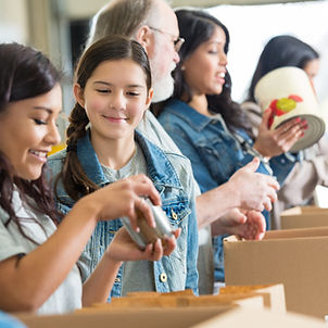 Children and volunteers packaging meals for community food bank